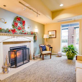 A cozy living room featuring a fireplace, comfortable seating, and decorative plants.