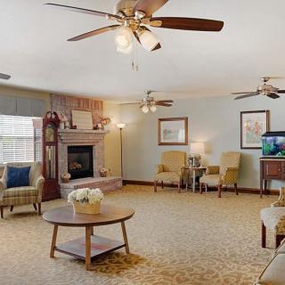 A spacious living room featuring a cozy fireplace, multiple ceiling fans, and comfortable seating.