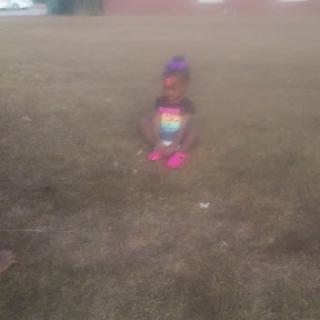 A child enjoying a playful moment outside in the grass.
