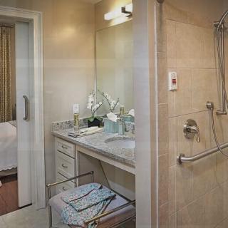 A modern bathroom featuring a sink with a mirror, a walk-in shower, and neatly organized towels.