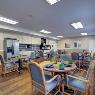 A spacious dining area with multiple tables and chairs, adjacent to a well-equipped kitchen.