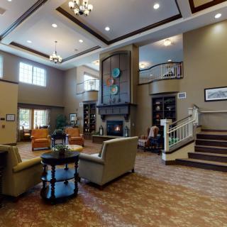 A modern lobby interior with comfortable seating, a fireplace, and elegant chandeliers.