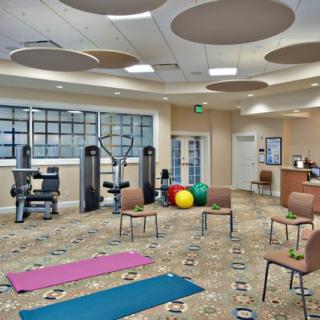 A modern fitness center with exercise equipment, yoga mats, and fitness balls arranged neatly in a spacious room.