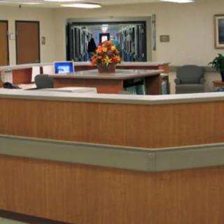 Hospital reception area with a central desk and floral arrangement.