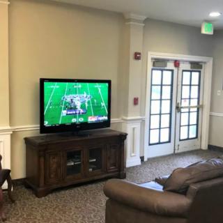 A comfortable living room with a TV displaying a football game.