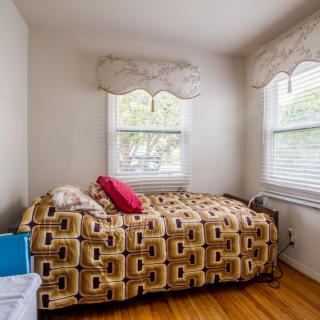 A cozy bedroom with a single bed, decorative quilt, and two windows letting in natural light.