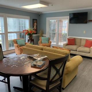 Cozy living room with comfortable seating, a television, and large windows.