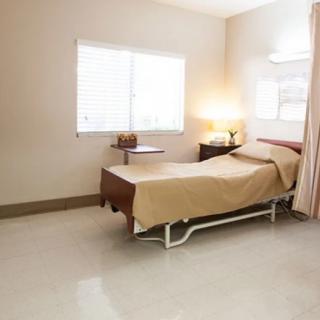 A clean and tidy hospital room with a bed, window, and a lamp on a bedside table.