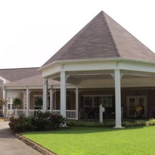 A building with a prominent entrance featuring columns and well-maintained landscaping.