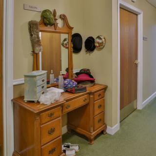 A wooden vanity with a mirror in a hallway, adorned with hats and various items.
