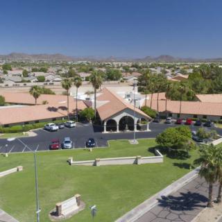 Aerial view of a church surrounded by palm trees and a suburban neighborhood.