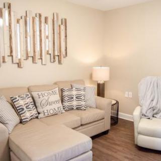 A stylish and cozy living room featuring a comfortable sectional sofa with decorative pillows, complemented by modern wall art and warm lighting.
