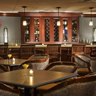 A cozy bar interior with wooden furniture and a wine rack.