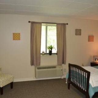 A cozy bedroom with a bed, chair, window, and simple decor.