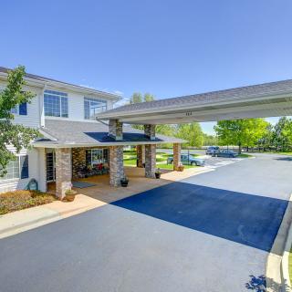 A modern building entrance with a covered driveway and surrounding greenery.