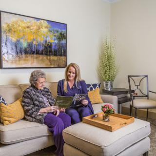 A caregiver and an elderly woman enjoying a moment of companionship in a cozy living room.