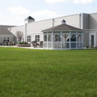 A gazebo situated on a well-maintained lawn outside a large building.