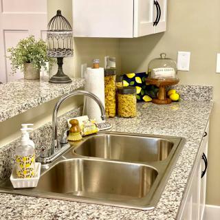 A well-organized kitchen countertop featuring a double sink, decorative elements, and neatly arranged jars.