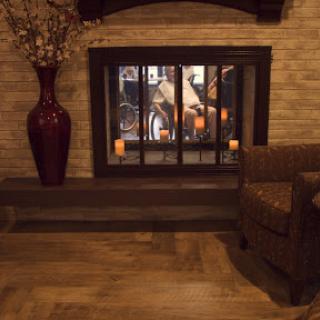 A cozy living room featuring a decorative fireplace, a comfortable chair, and elegant floral accents.