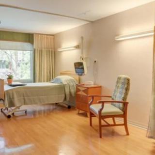 A clean and well-lit hospital room with a bed and chair.