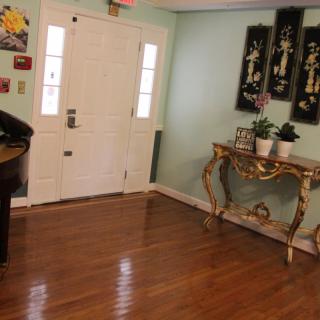 A well-decorated entryway with a door, side table adorned with plants and decorative items, and artwork on the walls.