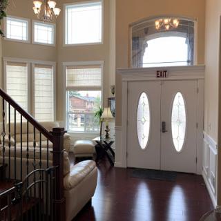A bright and elegant foyer characterized by large windows, modern decor, and warm wooden flooring.