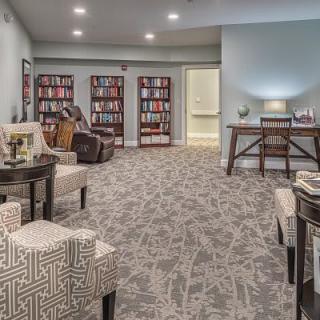 A cozy library space with bookshelves, comfortable seating, and an office desk.