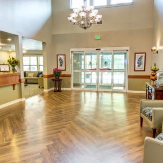 A bright and modern lobby with wood flooring and a chandelier.
