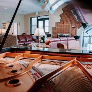 A cozy living room with a grand piano and a fireplace.