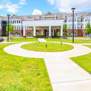A modern building with a circular walkway and well-maintained lawn under a bright blue sky.