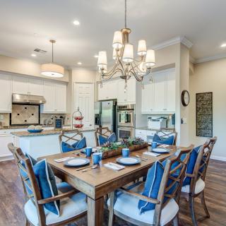 A modern kitchen and dining area with a wooden table set for a meal, complemented by a chandelier and stylish decor.