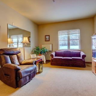 A cozy living room with a sofa, armchair, and warm lighting.