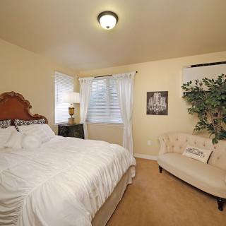 A cozy bedroom with elegant decor, featuring a comfortable bed, sofa, and soft lighting.