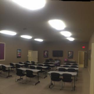 A spacious and well-lit classroom setup with tables and chairs, ready for an educational session.