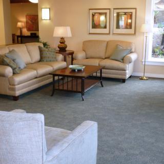 A cozy living room with comfortable sofas and a coffee table, featuring warm lighting and decorative artwork.