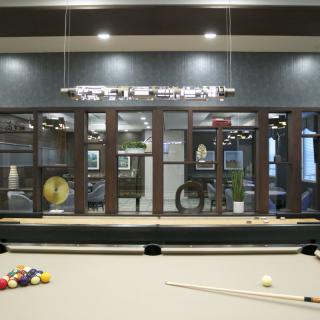 A modern recreation room featuring a pool table with billiard balls and a cue stick ready for play.