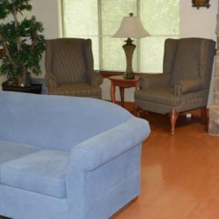 A cozy living room with a blue sofa, armchairs, and a table lamp.
