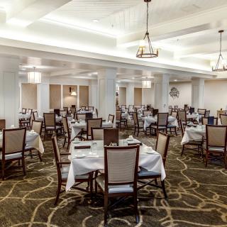 A spacious, elegantly decorated restaurant dining room with neatly set tables and comfortable chairs.