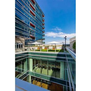 A modern office building with a glass facade and an open outdoor space under a clear blue sky.