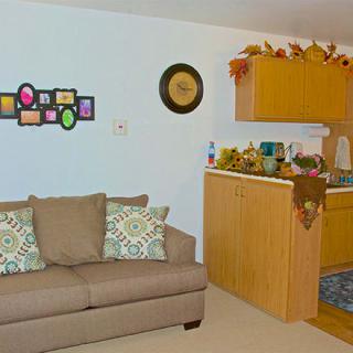 A cozy living room with a sofa and a decorated kitchen area.