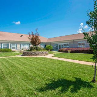 A well-maintained building with a green lawn and clear blue sky.