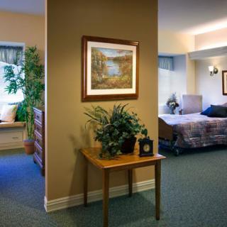 A cozy, well-decorated interior space featuring a bed, plants, and wall art, suggesting a welcoming, home-like environment.