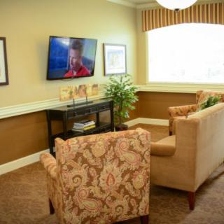 A cozy living room with armchairs facing a mounted television.