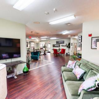 A modern living room with a green sofa, large TV, and stylish decor.
