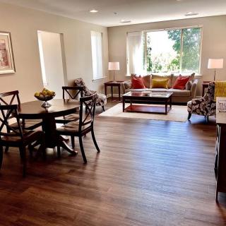 A spacious living room with hardwood flooring, featuring a comfortable seating area and a dining table.