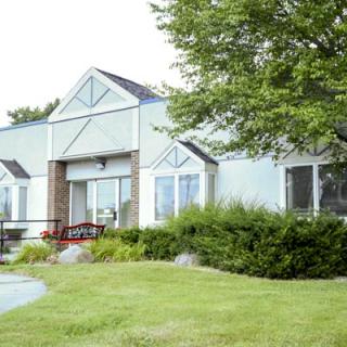 A suburban house with a well-maintained lawn and surrounding greenery.