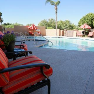A sunny outdoor swimming pool area with comfortable patio furniture.