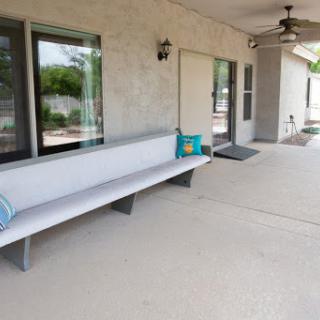 A modern outdoor patio area featuring a sleek bench and ceiling fan, perfect for relaxation.