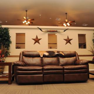A cozy living room featuring a brown leather couch, decorative stars on the wall, and warm lighting from ceiling fans.