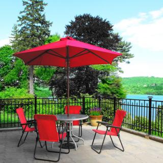 A tranquil patio setting with red chairs and umbrella overlooking a picturesque lake.